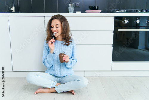 Lovely happy exuberant woman with wavy brown hair eating delicious chocolate cream and closing her eyes from pleasure.
