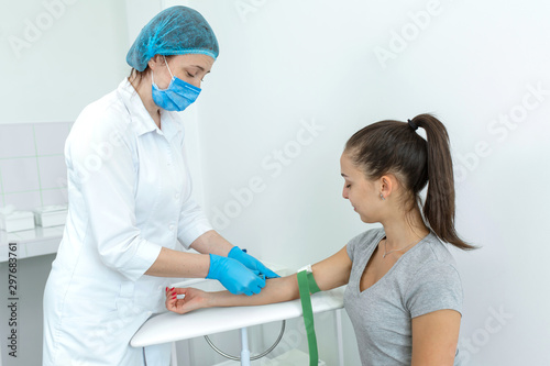 A nurse inserts a needle into a vein on a patients arm. Blood sampling procedure