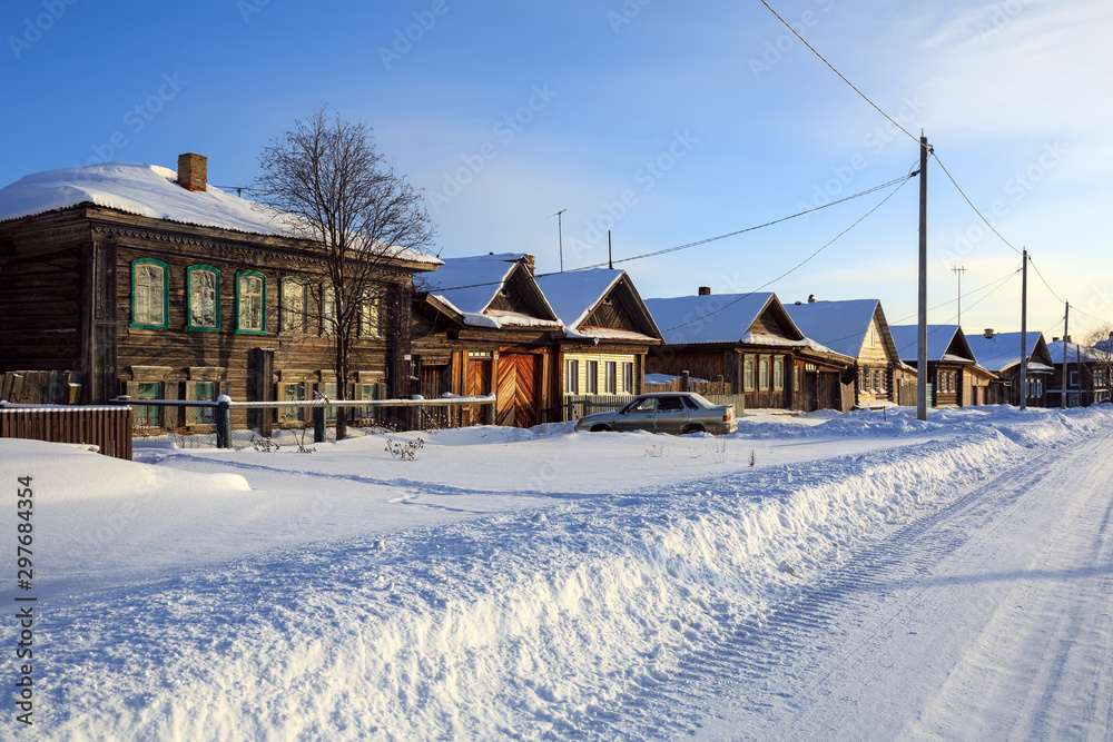 Snow-covered village street in winter. Traditional wooden houses. Village of Visim, Sverdlovsk region, Russia.