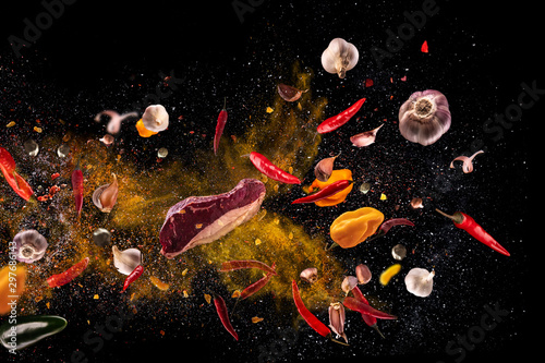 Hot red pepper, garlic, different spices powder meat stakes flying on a black background Motion freeze photo composition photo