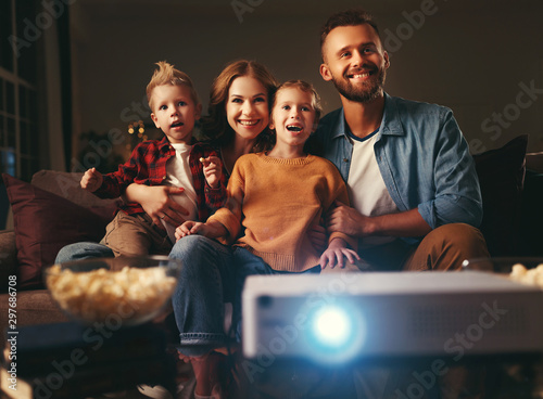 Bild auf Leinwand family mother father and children watching projector, TV, movies with popcorn in   evening   at home