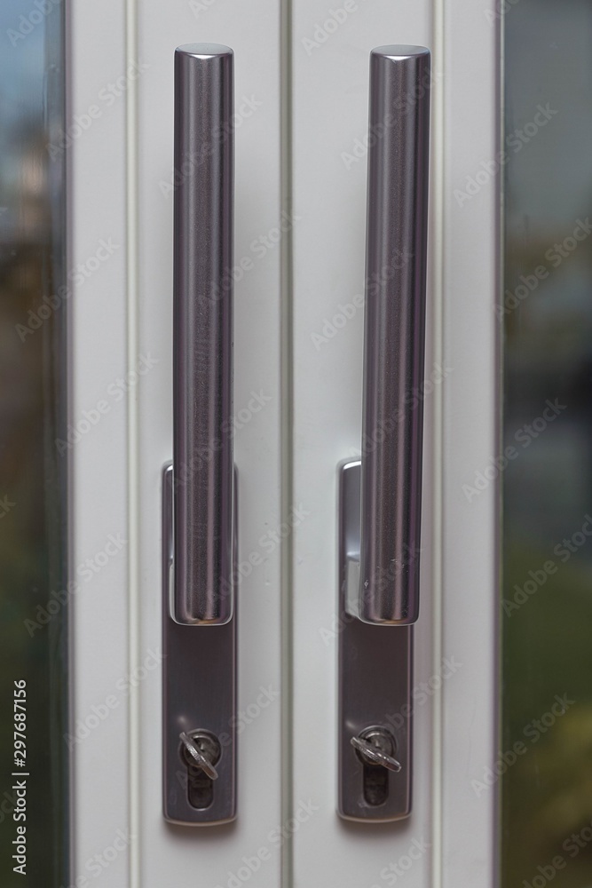 Close up view of steel door handles on glass doors isolated. Interior design concept. Close up view of steel door handles on glass doors isolated. Interior design concept.