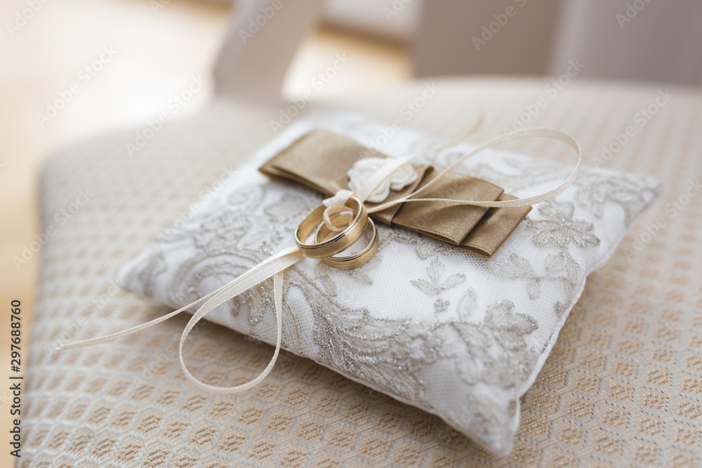 Golden wedding rings lies on a small decorated pillow Golden wedding rings lies on a small decorated pillow