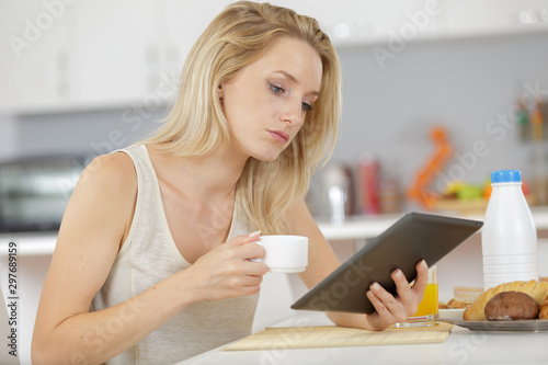 woman in the home holding cup and using a tablet