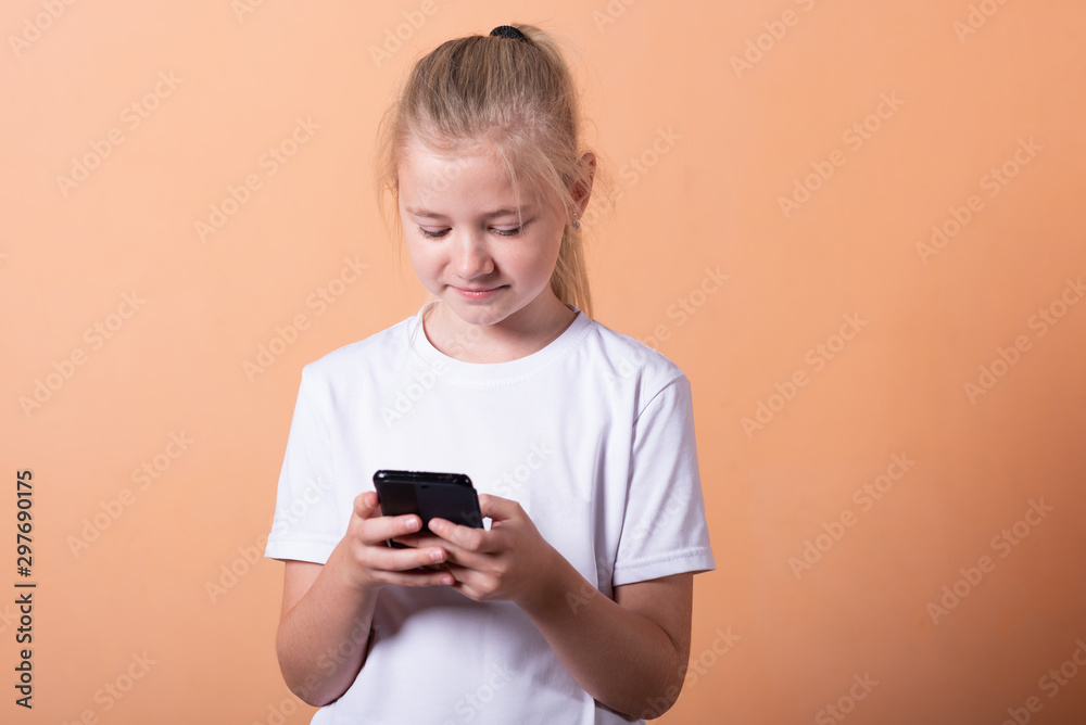 Little girl with a smartphone on a light orange background. Little girl with a smartphone on a light orange background.