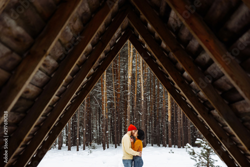 Happy couple in love walks in the winter forest. Theу kisses and hugging each other with love