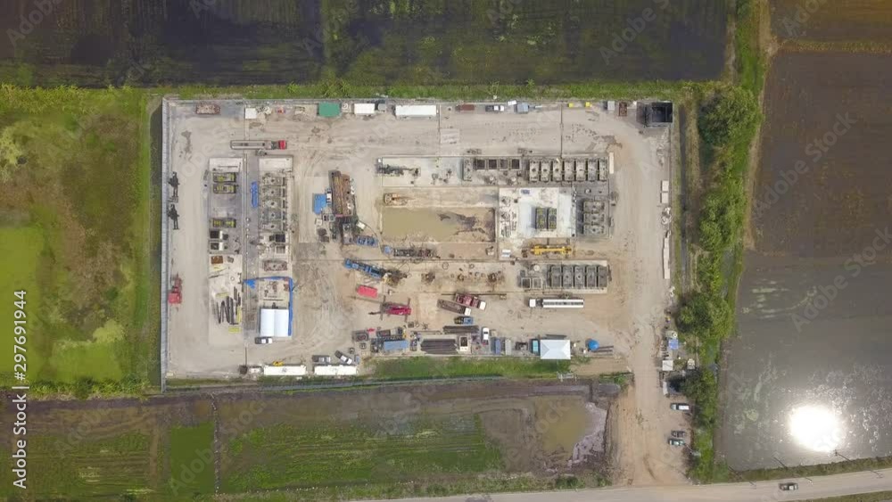 Oil and gas a land rig, onshore drilling rig, in the middle of a rice field aerial view from a drone Oil and gas a land rig, onshore drilling rig, in the middle of a rice field aerial view from a drone