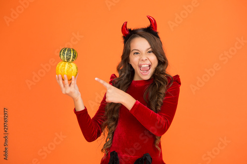 Very spooky. Happy girl point finger at pumpkins orange background. Small child with spooky Halloween look. Have frightfully spooky Halloween. Spooky and scary