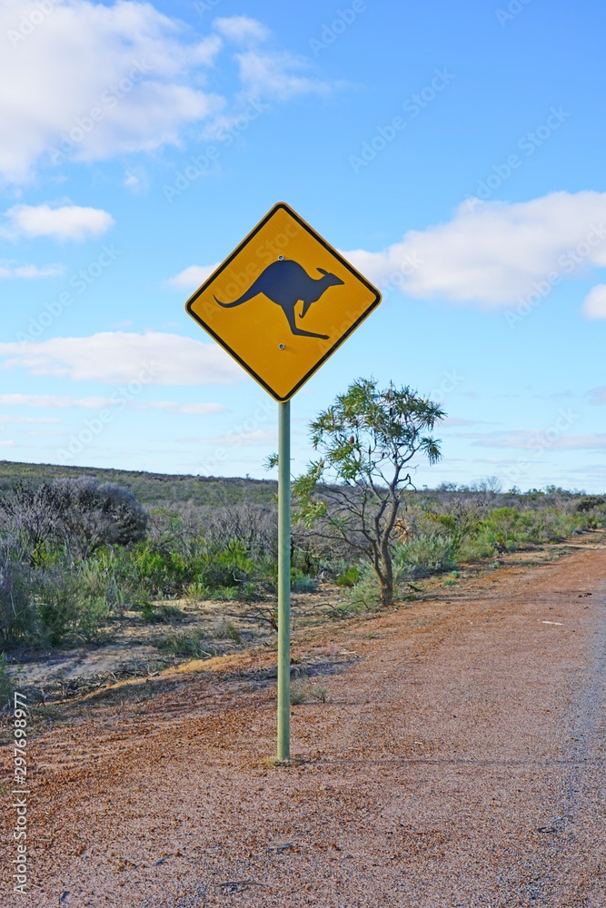 A yellow kangaroo crossing road sign on the road in Western Australia A yellow kangaroo crossing road sign on the road in Western Australia