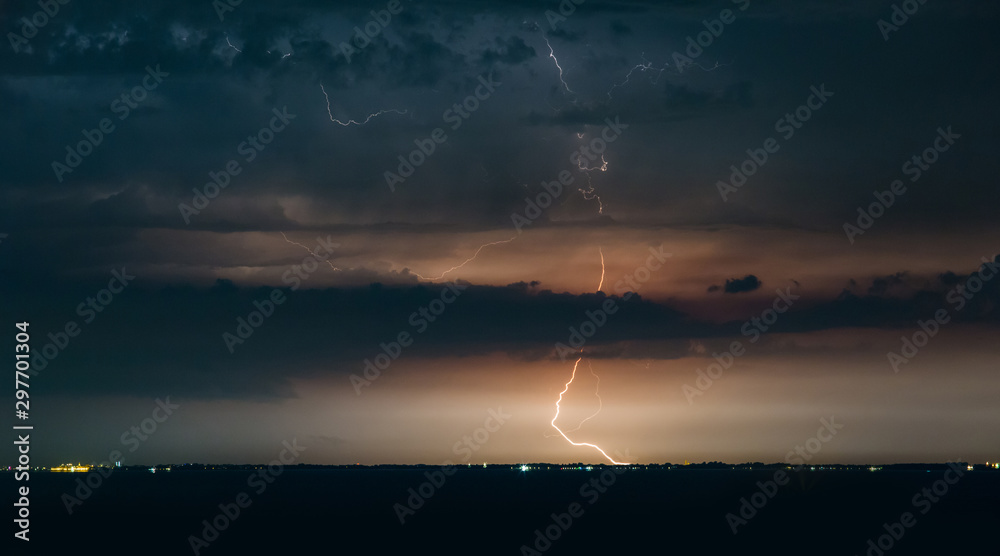 Massive drammatic cloud to ground lightning bolts hitting the horizon of city lights Massive drammatic cloud to ground lightning bolts hitting the horizon of city lights