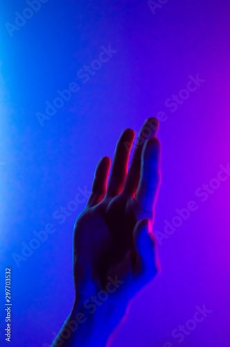 Hands in colorful blue red contrast neon light. Man showing hand palm gesture sign. Vertical orientation photo. Trendy party club style illumination.