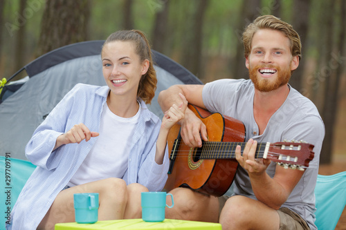 happy couple with guitar near the tent