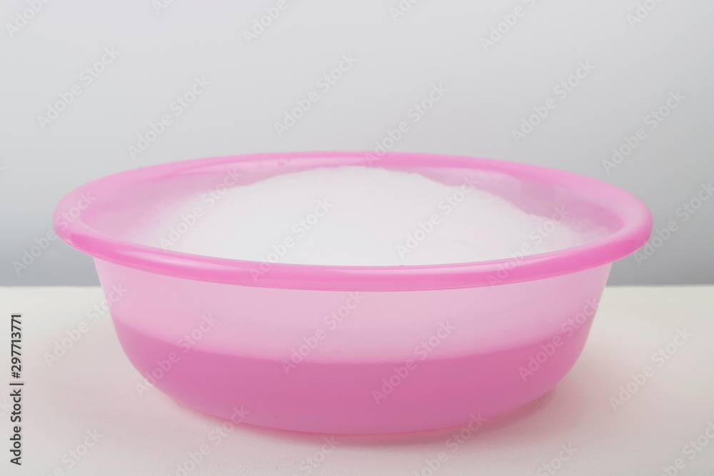 Pink wash basin with thick soapy foam on white background Pink wash basin with thick soapy foam on white background