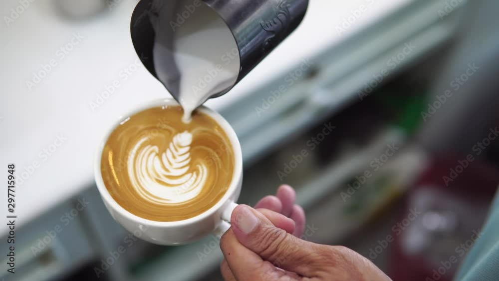 barista pouring milk to make coffee latte art. b-roll footage video 4k. cafe business shop.