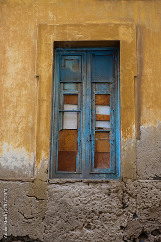 Beautiful pale blue wooden window frame in a wall of an old decaying building.