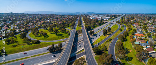 Straight road passing through interchange and leading to mountains in the distance. Aerial view in Melbourne, Australia