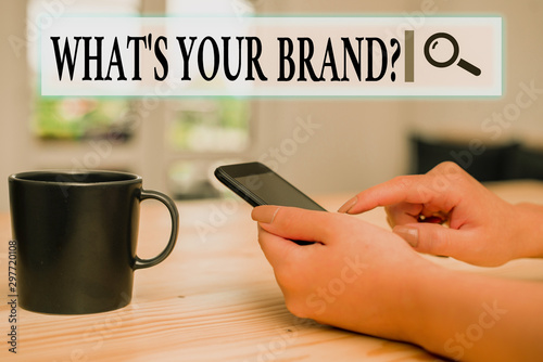 Writing note showing What S Your Brand Question. Business concept for asking about product logo does or what you communicate woman using smartphone and technological devices inside the home photo