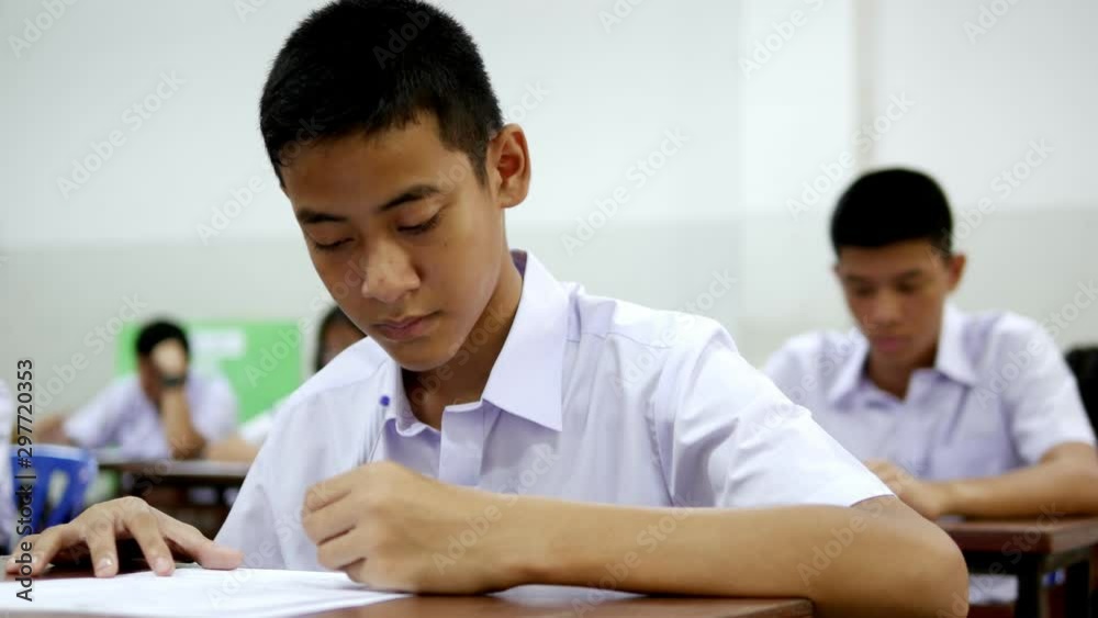 Asian high school students in white uniform are doing examinations. Asian high school students in white uniform are doing examinations.