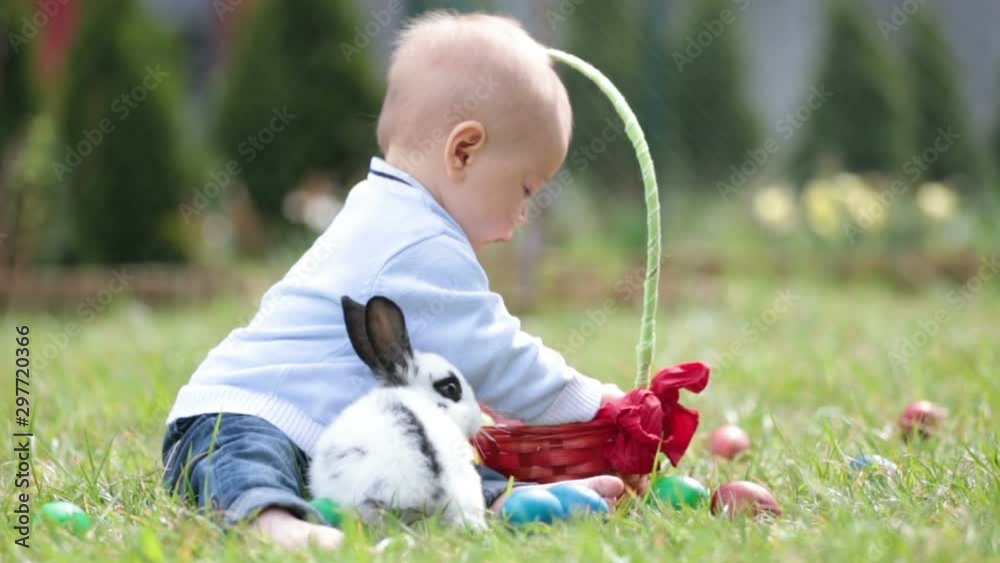 Sweet little baby boy hunting for easter egg in spring park on Easter day. Cute little child with adorable cute bunny celebrating feast outdoors Sweet little baby boy hunting for easter egg in spring park on Easter day. Cute little child with adorable cute bunny celebrating feast outdoors