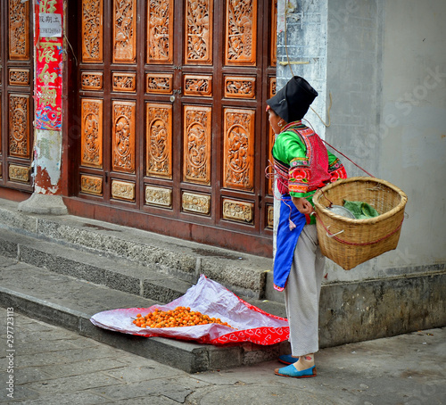 Bai woman selling loquats in the streets of Dali ancient city, Yunnan province, China.	