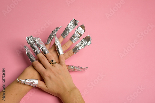 The procedure for removing varnish from nails hybrid nails in progress. Gel nail polish remover foils on woman's hands.