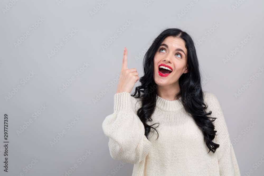 Young woman looking upwards on a gray background Young woman looking upwards on a gray background