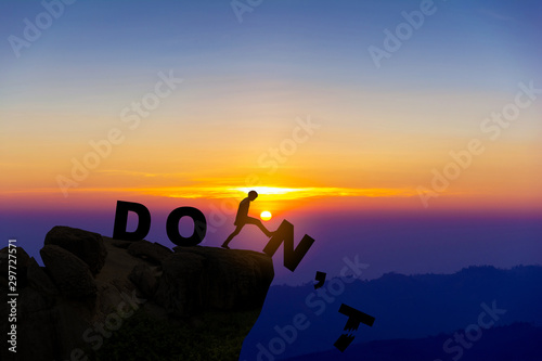 Silhouette man pushing letters N and T from the rock. Word 'do' standing sound. Sunrise sky at background. Concept of opportunity,copy space.