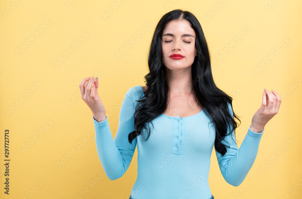 Young woman in a meditation pose on a yellow background Young woman in a meditation pose on a yellow background