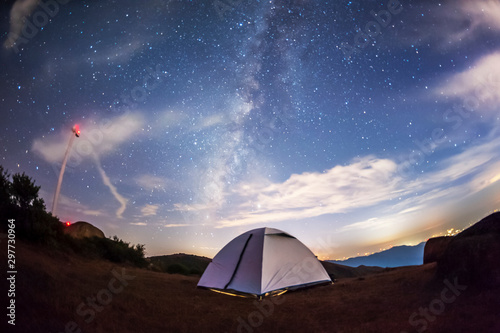 Camping tent under the stars and distant city background
