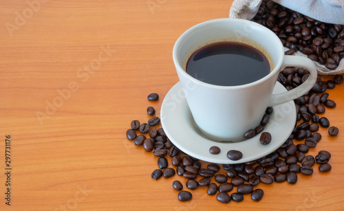 A cup of coffee with coffee beans on the wooden table