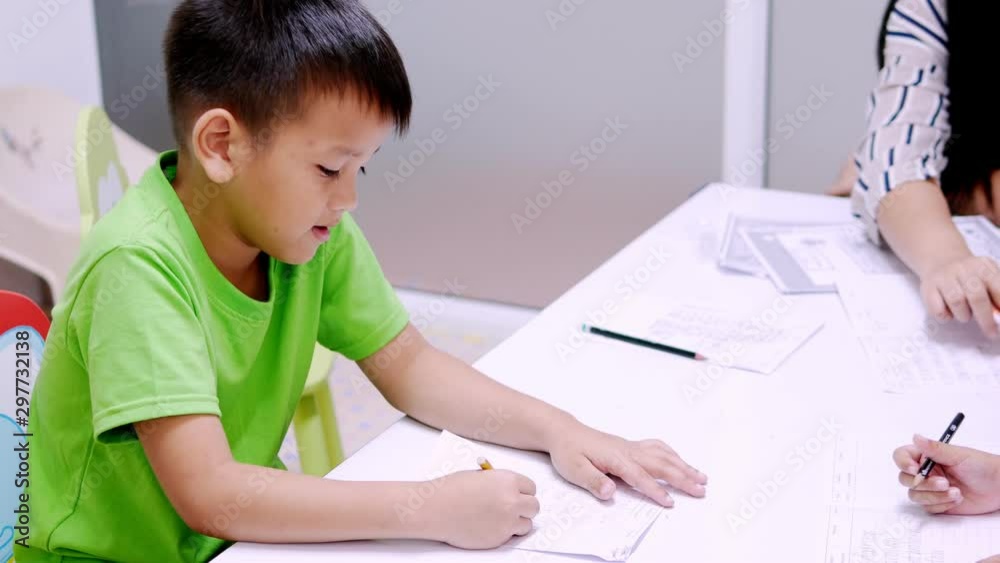 Asian elementary school boy is studying in the classroom with an Asian woman teacher. Asian elementary school boy is studying in the classroom with an Asian woman teacher.