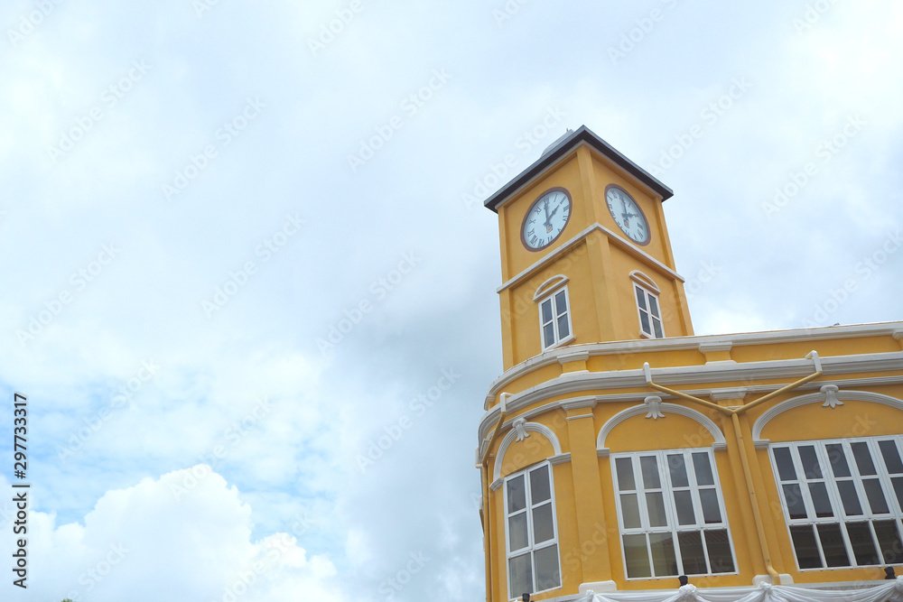 The yellow clock tower in  old building with cloudy at Phuket city, Thailand.