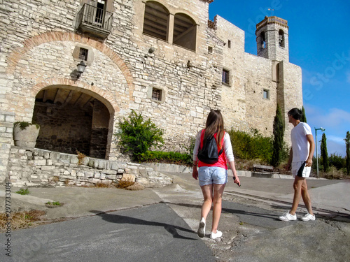 A couple of tourists approach to the walls of the castle Montfalco Murallat, La Segarra, Lleida province in Catalonia, Spain. Slender man and woman in comfortable clothes travel to medieval fortress photo