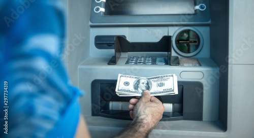 Man holding dollars withdrawn from ATM.