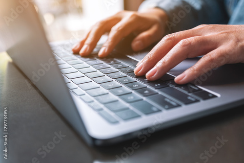 Closeup image of a woman working and typing on laptop computer on the table photo