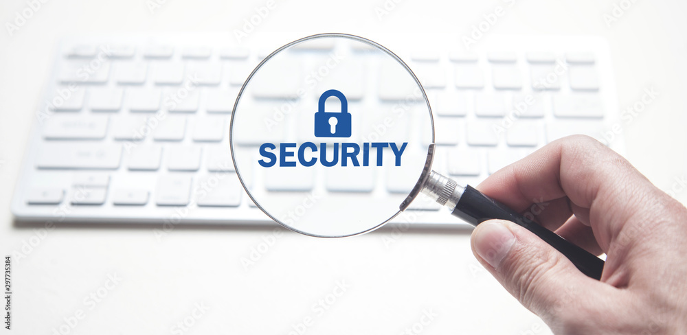 Hand holding magnifying glass on computer keyboard. Security Hand holding magnifying glass on computer keyboard. Security