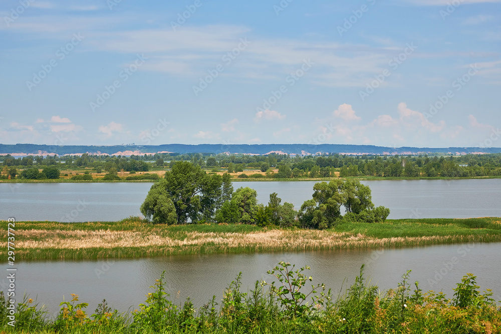 A small island on the Volga river. Trees and grass grow on the island. A small island on the Volga river. Trees and grass grow on the island.
