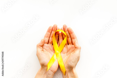 Disease control concept. Orange ribbon in hands on white background top view copy space