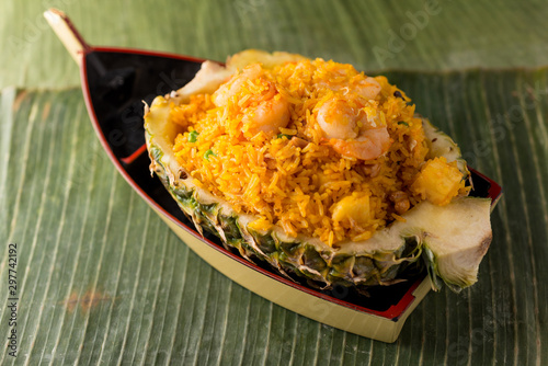 Malaysian Pineapple Shrimp Fried Rice with peas and cashew nuts. Served in a pineapple shell, plated in a boat, on banana leaves