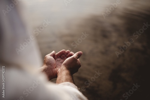 Fototapeta Beautiful shot of a male wearing a biblical robe holding water with his palms