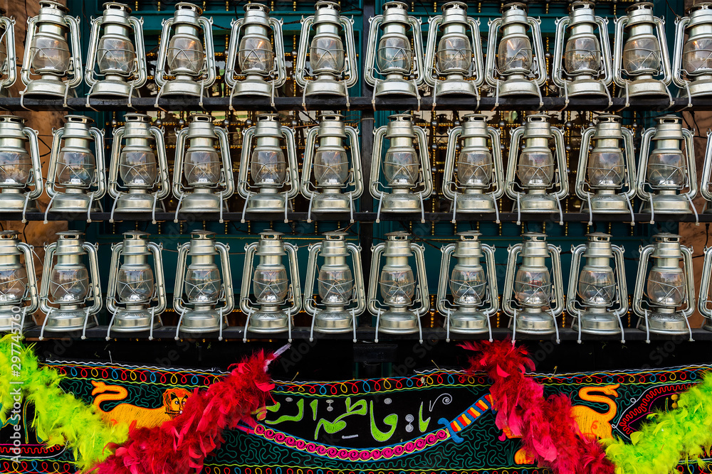 Fototapeta premium kerosene lamps and the name Fatima embroidered on fabric in front of a mosque, as a symbol of religious mourning of Imam Husayn martyrdom, Tehran, Iran