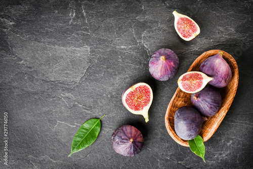 Fresh figs in wooden table on black background. Ripe citrus fig cut fruits on dark stone table from top view.