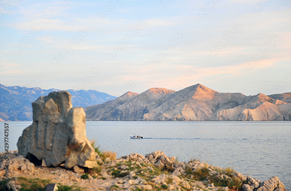Speed boat, mountains and ancient letters monument on Krk