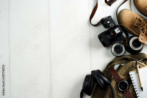Camping or adventure trip scenery concept. Backpack, boots, belt, thermos and camera on wooden background captured from above (flat lay). Layout with free text (copy) space.