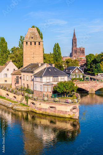 Close-up on the Heinrichsturm tower and the Ponts Couverts (covered bridges) on the river Ill in the Petite France historic quarter in Strasbourg, France, with Notre-Dame cathedral in the distance. photo