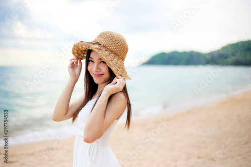 Beautiful girl young woman asia in a  hat smiling on the beach at sunset,enjoy summer vacation on the beach.