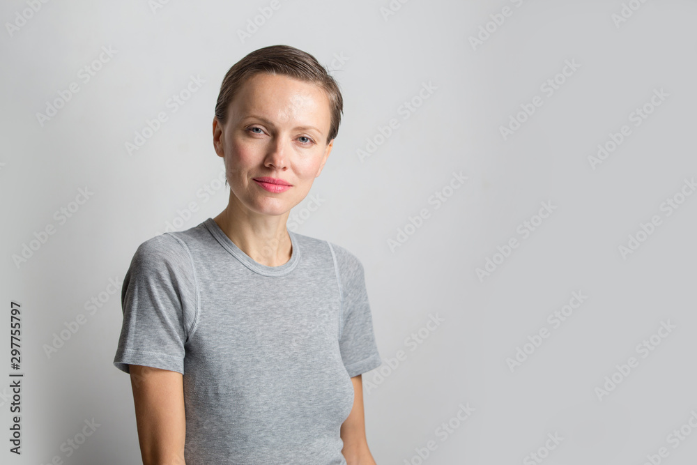 Happy cheerful young woman with short hair, natural makeup over light white grey background. Indoor portrait of beautiful brunette young woman Happy cheerful young woman with short hair, natural makeup over light white grey background. Indoor portrait of beautiful brunette young woman