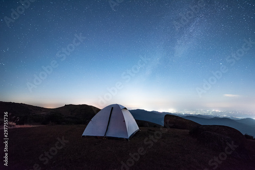 Tourist hikers tent in mountains at night with stars in the sky 