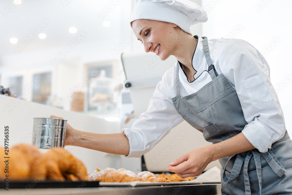 Confectioner woman powdering cocoa on sweet bread Confectioner woman powdering cocoa on sweet bread