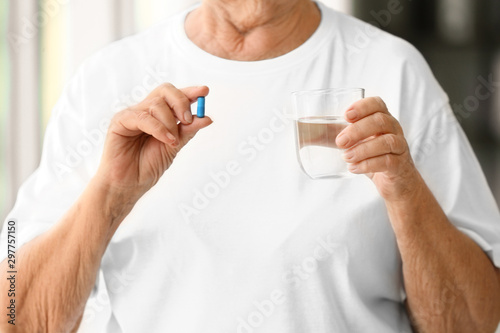 Elderly woman taking pill at home, closeup